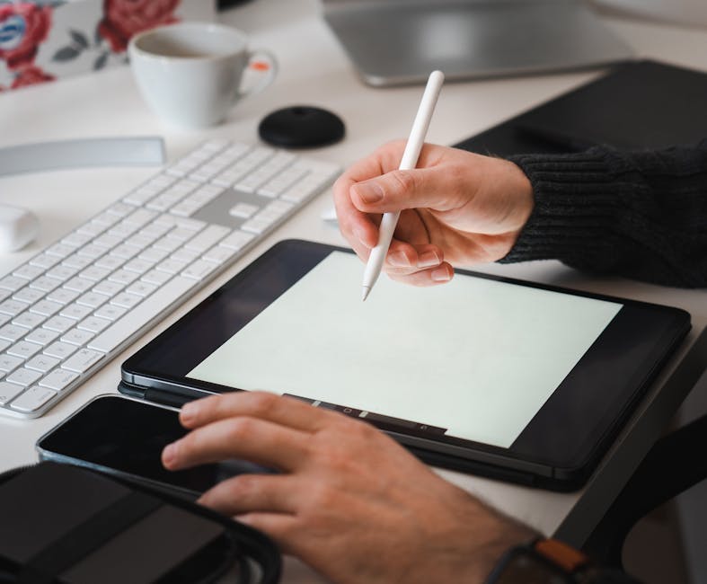 Designer working with a tablet and stylus in a modern workspace setup.